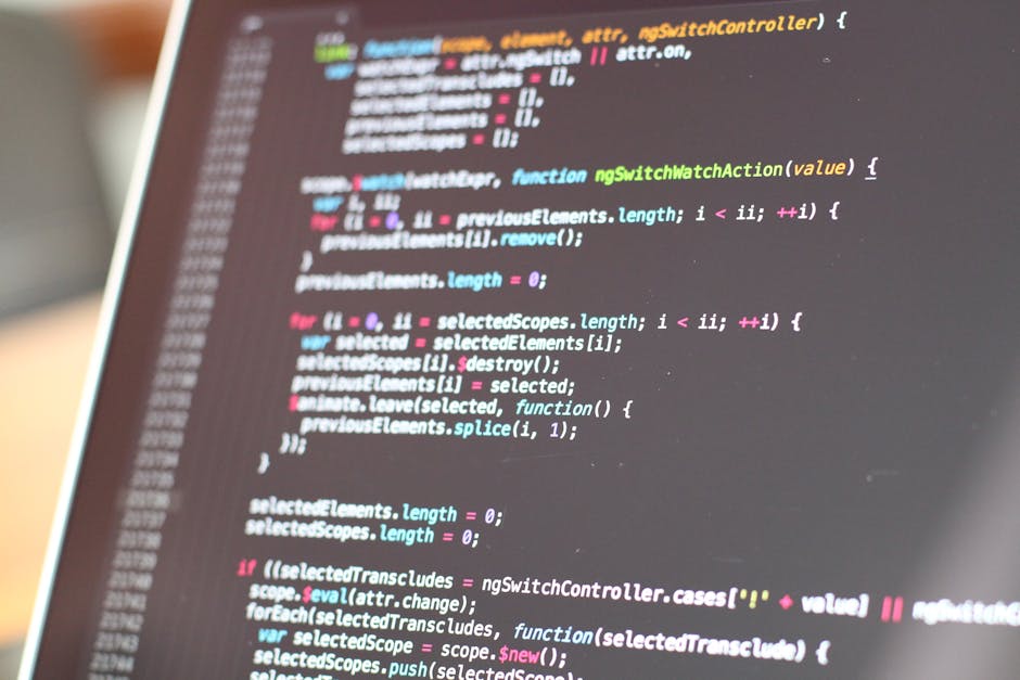 A close-up view of a computer screen displaying lines of colorful programming code, with syntax highlighting in shades of pink, green, blue, and white on a dark background. The screen is slightly tilt